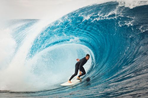 Person surfing inside a large, curling ocean wave.